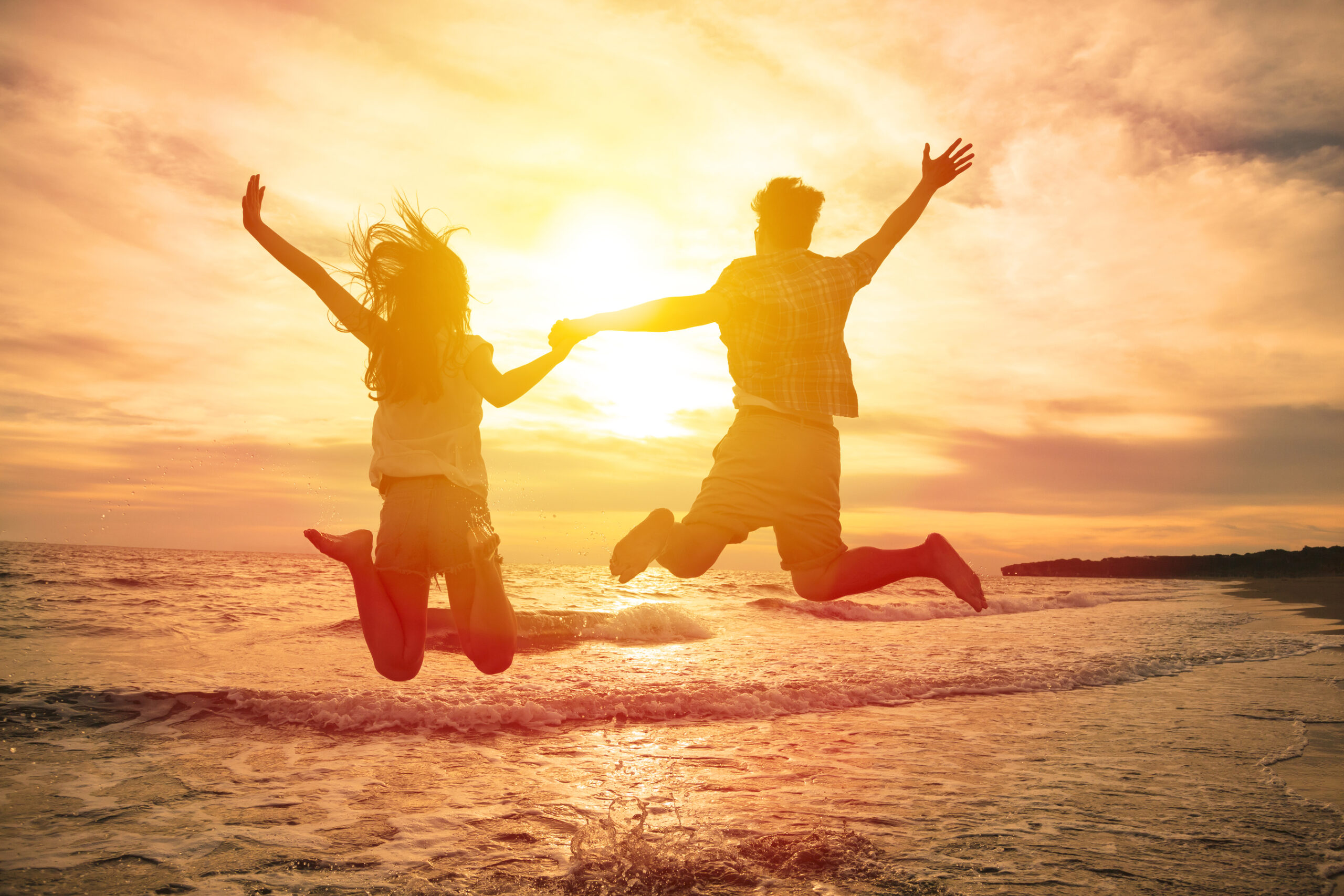 young happy couple jumping on beach